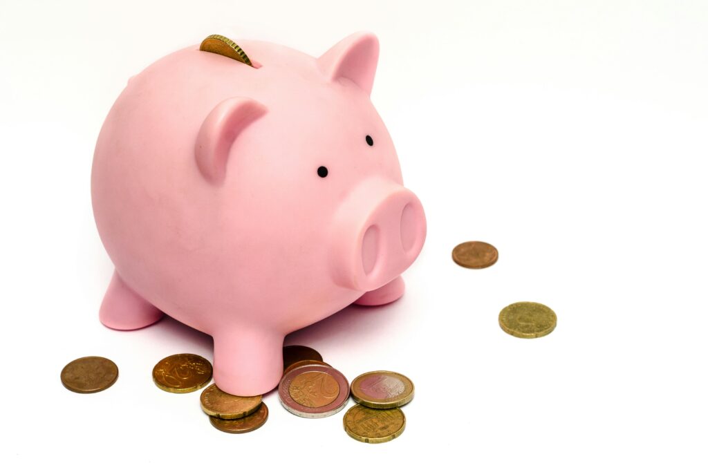 Tirelire cochon rose avec des pièces éparpillées autour, symbolisant les économies d'énergie.